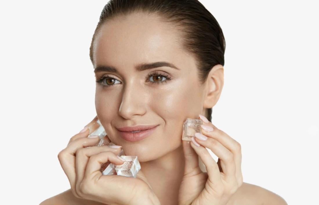A smiling woman applying ice on her face after facial