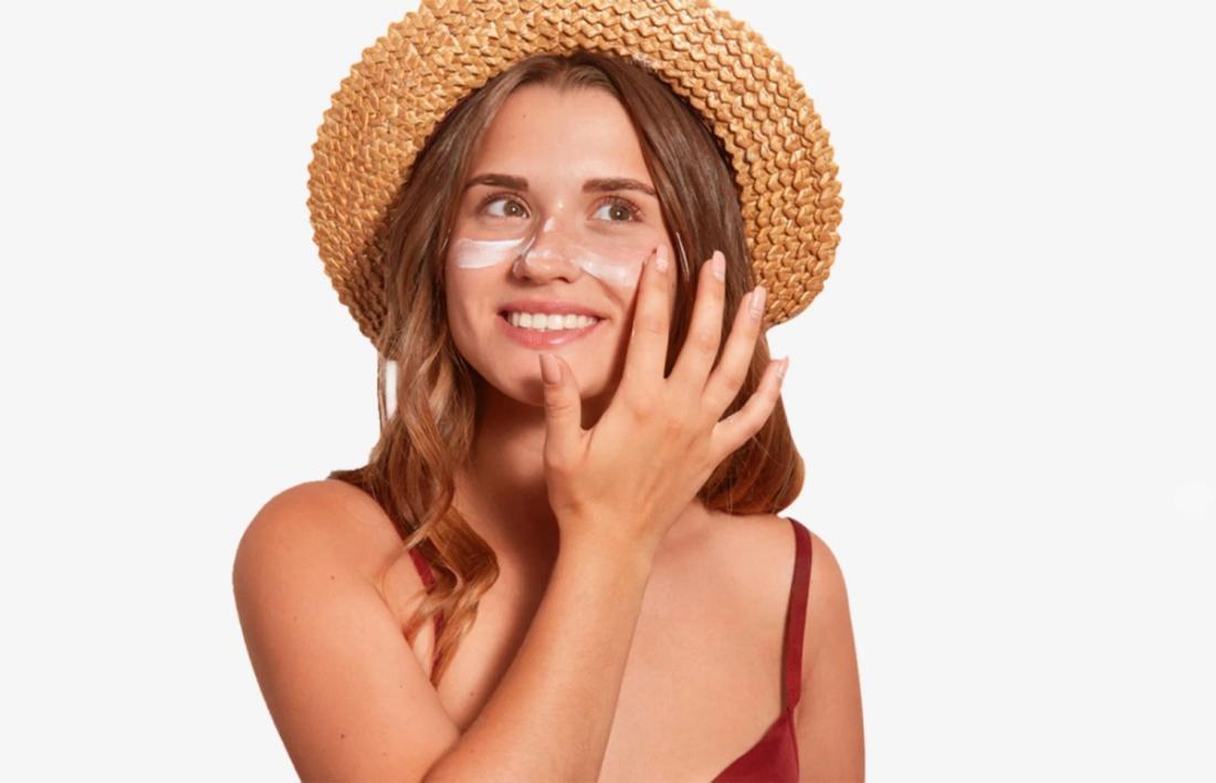 A woman smiling with beach hat after applying cream